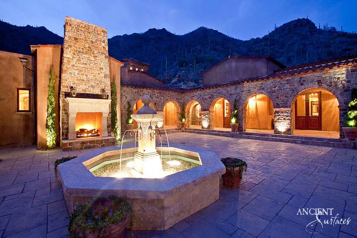 Illuminated octagonal limestone pool fountain with a central column in a twilight courtyard