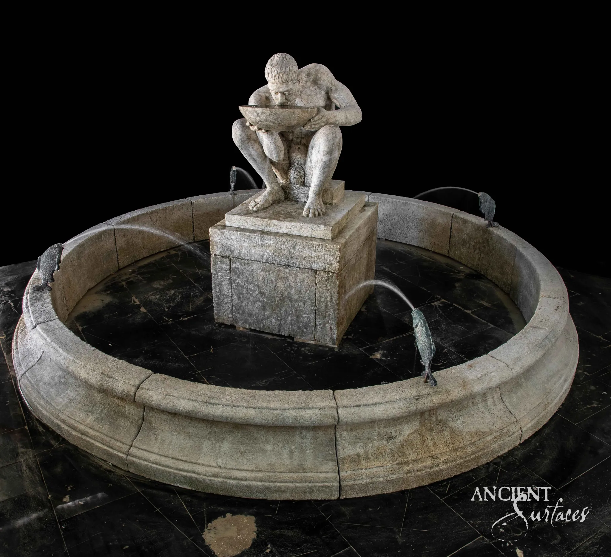 Round limestone pool fountain with a carved crouching figure centerpiece and bronze fish spouts